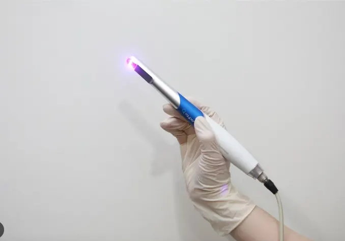 장갑을 낀 손에 들린 형광 진단기, 끝에서 보라색 빛이 나오고 있다